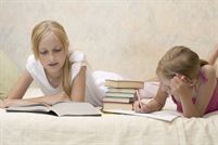 Two sisters do homework on sofa